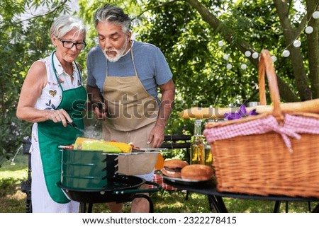Elderly couple celebrate the 4th of July in their backyard. They are making barbeque, vegetables, and drinking beverages while enjoying and making memories