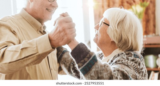 Elderly couple dancing joyfully. Seniors enjoying a dance. Happy elderly pair holding hands. Bright, cheerful moment of elderly joy and connection. Senior couple in love, dancing and enjoying life. - Powered by Shutterstock