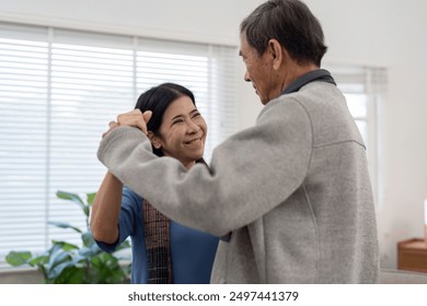 Elderly Couple Dancing and Smiling Together in a Bright, Cozy Living Room with Natural Light - Powered by Shutterstock