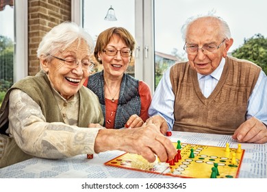 Elderly Couple And Daughter Playing Board Game