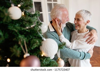 Elderly couple decorating a Christmas tree  - Powered by Shutterstock