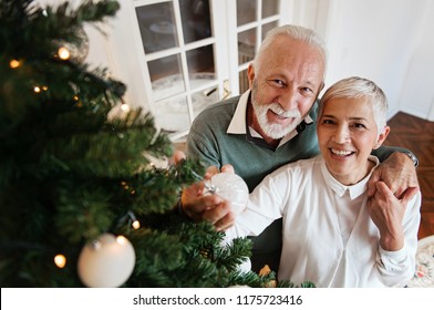 Elderly couple decorating a Christmas tree  - Powered by Shutterstock