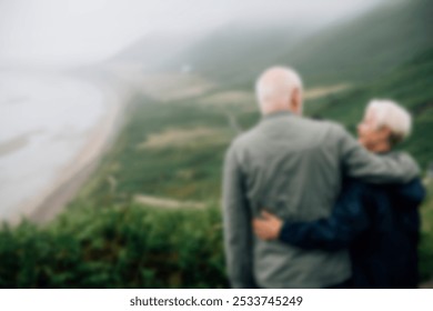 Elderly couple embracing, overlooking a misty coastal landscape. The couple enjoys the serene view, symbolizing love and companionship in nature's beauty. Happy retirement of elderly couple in nature - Powered by Shutterstock