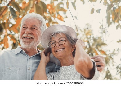 Elderly Couple Embracing In Spring Park Outdoors Having Fun And Enjoying Together Looking At The Trees. Two Old And Mature People In Love Caring Each Other.