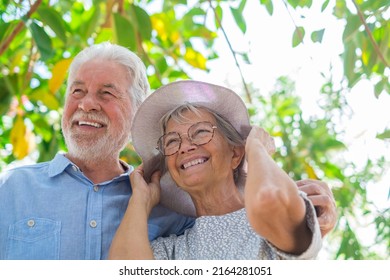 Elderly couple embracing in spring park outdoors having fun and enjoying together looking at the trees. Two old and mature people in love caring each other. - Shutterstock ID 2164281051