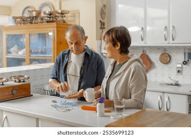 An elderly couple engages in a thoughtful discussion about medication management within a cozy kitchen setting, standing in casual clothing. Organizing pill box, daily routine at home. Horizontal - Powered by Shutterstock