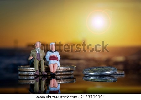 Elderly Couple Golden Age Inflation Pensions Sitting Coin Pile Sunset Miniature People Figures Background