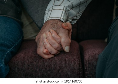 elderly couple hands intertwined on the sofa