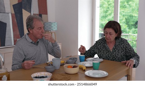 Elderly couple having a conversation over breakfast, emphasizing their morning routine, connection, and companionship in a bright, comfortable home - Powered by Shutterstock