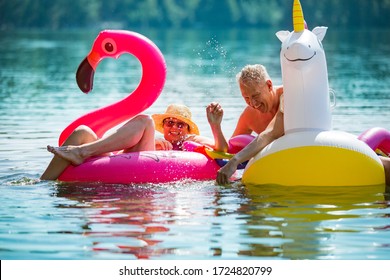 Elderly couple having fun on inflatable flamingo and unicorn. Funny active pensioners happy together enjoying summer vacation on the beach in Europe, laughing, playing the fool, splashing water. - Powered by Shutterstock