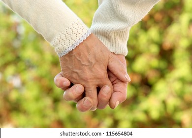 Elderly Couple Holding Hands In Autumn Park