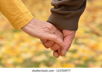 Elderly Couple Holding Hands In Autumn Park