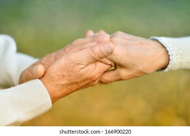 Elderly Couple Holding Hands In Autumn Park