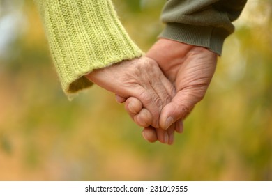 Elderly Couple Holding Hands In Autumn Park