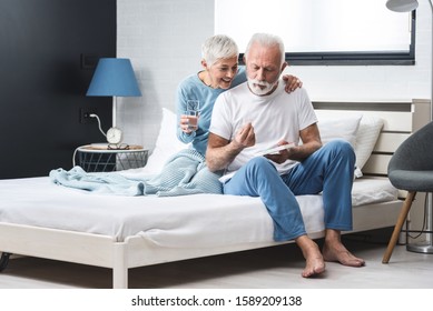 Elderly couple at home, senior grey haired man and woman take pill medicine for medical health care while sitting on bed,  concept couple take vitamin - Powered by Shutterstock