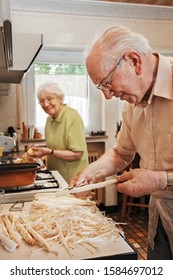 Elderly Couple in the Kitchen Preparing Potatoes and Asparagus