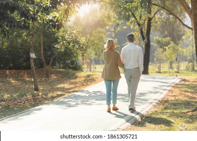 Elderly Couple Lifestyle Concept. Husband And Wife And Sit Walking In The Park.