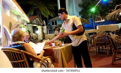 Elderly couple looking at the menu. Before them stands the waiter and is about to write down the order. A scene in a street restaurant, evening. India, Goa - November 2, 2017. - Shutterstock ID 767450911