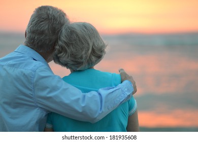 Elderly couple in love at sunset on a summer evening watching sea