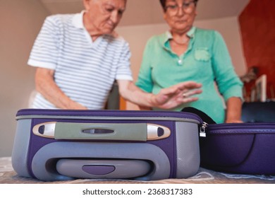 An elderly couple packing suitcases for a trip. - Powered by Shutterstock