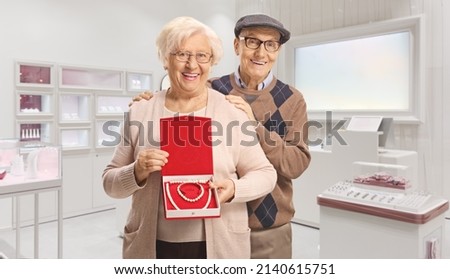 Elderly couple with a pearl necklace and bracelet in a box standing inside a jewlery store