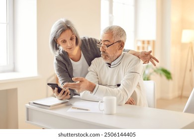 Elderly couple of pensioners happily view photos on phone reminiscing cherished memories. With smiles on faces they view photos on phone enjoy moments captured in photographs view photos on phone - Powered by Shutterstock