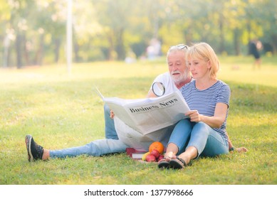 Elderly couple reading newspaper in garden at sunset. Concept couple elder love.