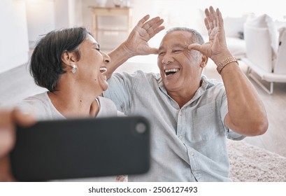 Elderly couple, selfie and happy in home for love, funny and silly face in retirement. Laugh, senior people and joke in living room for photography, bonding and tech for live stream or video call - Powered by Shutterstock