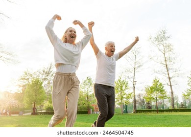 elderly couple of seniors man and woman rejoice in victory and run with raised hands in the park outdoors, gray-haired grandparents shout and celebrate luck and success and rejoice in nature - Powered by Shutterstock