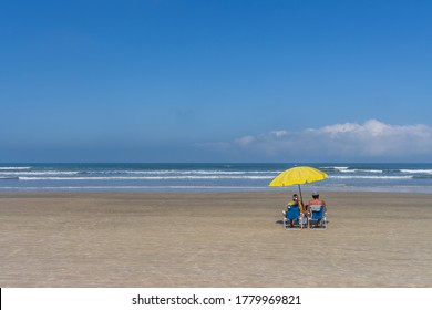 Elderly couple sitting by the sea sunbathing and relaxing on the beach. Reopening of beaches after quarantine. - Powered by Shutterstock