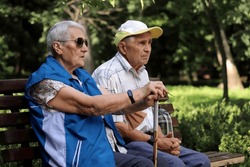 Elderly Couple Sitting On A Bench In Spring Or Summer Park. Old Man And Woman Outdoors, Life In Retirement