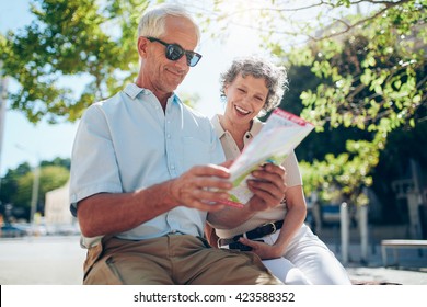 Elderly Couple Sitting Outdoors In The City Looking At A Map. Happy Senior Man With His Wife Using City Map.