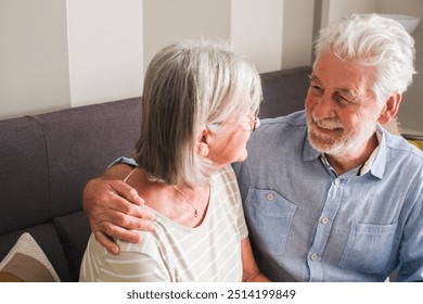 Elderly couple sitting together on a sofa, sharing tender moments and smiling as they engage in a warm conversation. Capturing the essence of mature love, mutual support, and happiness in their age - Powered by Shutterstock