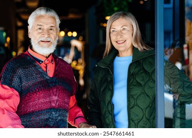 Elderly couple standing together, dressed warmly, smiling indoors. Older man with white beard and woman happiness and contentment, cozy atmosphere. Concept of Senior living, love, relationships. - Powered by Shutterstock