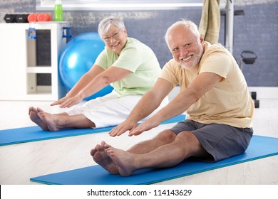 Elderly Couple Stretching In The Gym.