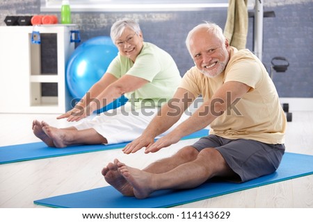 Elderly couple stretching in the gym.