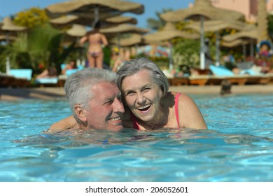 Elderly Couple Swimming In Pool At Hotel Resort