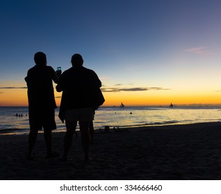 Elderly Couple Taking Pics From A Beautiful Sunset On A Tropical Beach 