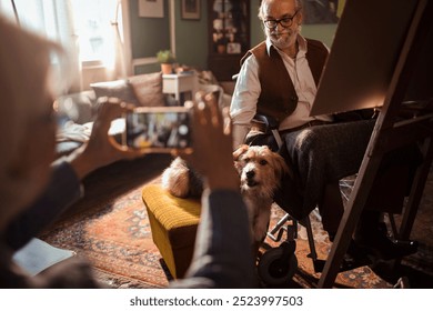 Elderly couple taking selfie while painting at home with their dog - Powered by Shutterstock