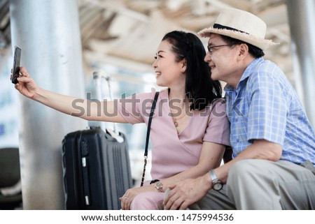 Elderly couple using a cell phone self-portrait while traveling abroad happily.
