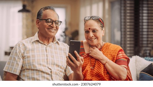 Elderly Couple Using Smartphone for Video Call at Home: Connecting with Family, Sharing Stories, and Celebrating Special Occasions. Cherishing Precious Moments Together. Medium Shot. - Powered by Shutterstock