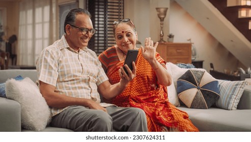 Elderly Couple Using Smartphone for Video Call at Home: Connecting with Family, Sharing Stories, and Celebrating Special Occasions. Cherishing Precious Moments Together. Medium Shot. - Powered by Shutterstock