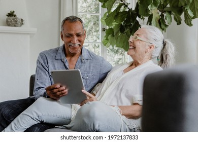 Elderly Couple Using A Tablet On A Couch