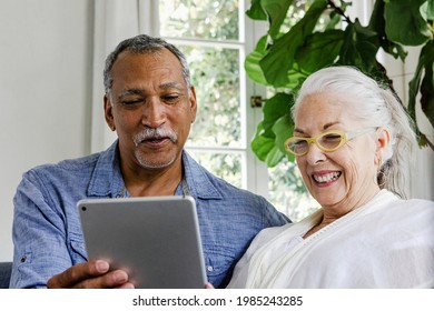 Elderly couple using a tablet on a couch