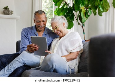 Ältere Paare, die eine Tablette auf einem Sofa benutzen