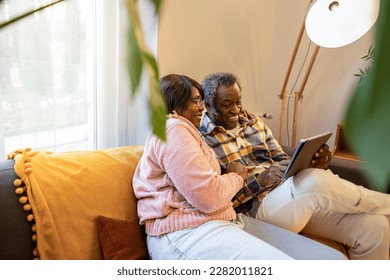 elderly couple video call with a tablet on the sofa at home - Powered by Shutterstock