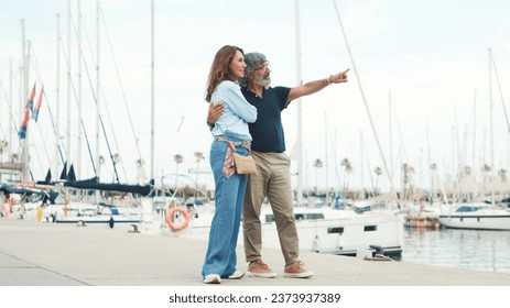 An elderly couple are walking along the promenade and having fun chatting on yacht background - Powered by Shutterstock