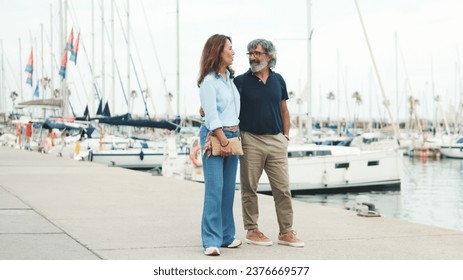 An elderly couple are walking along the promenade and having fun chatting on yacht background - Powered by Shutterstock