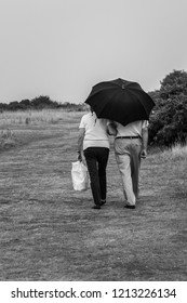 An Elderly Couple Walking Under An Umbrella In Walton On The Naze, Essex