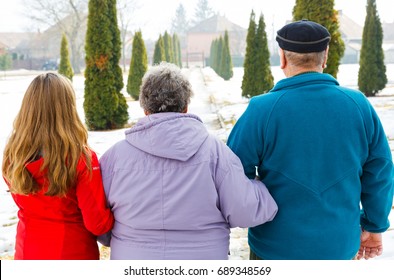 Elderly couple and young caregiver walking in the park in wintertime